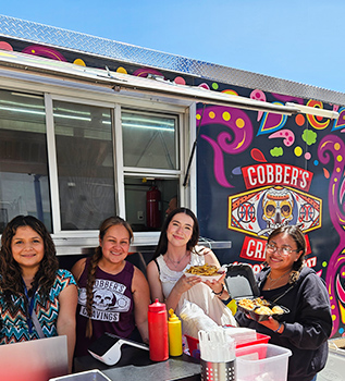 Group of happy women eating in front of Cobber's food truck