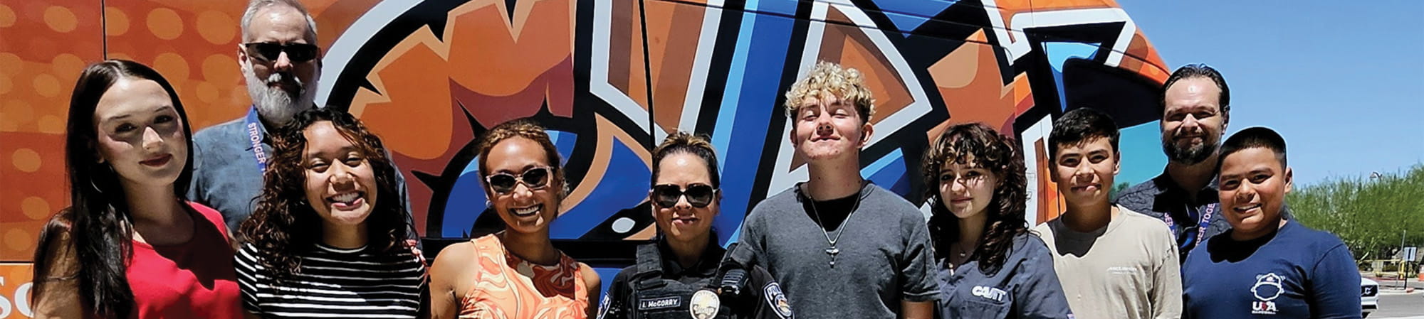 Students and teachers with a law enforcement officer by A+ bus