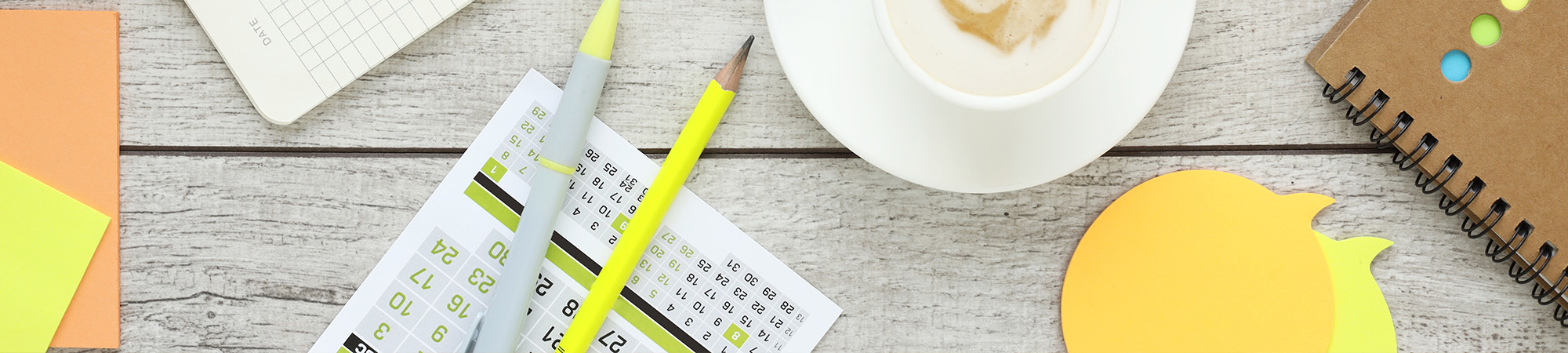 Desk with pencil, coffee, and notepads