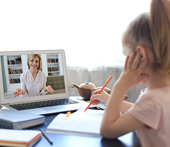 Elementary girl talking to a nice teacher online from home