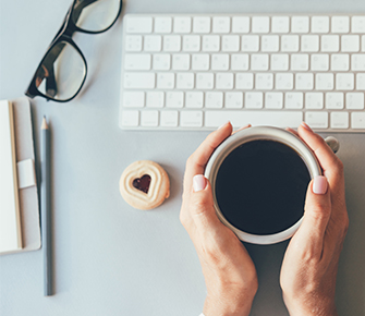 Teacher in front of computer with a cup of coffee
