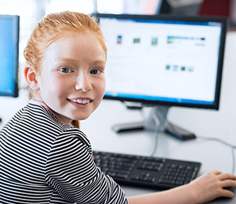 Middle school girl turning around from computer to smile for the camera