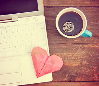 Laptop next to coffee and red paper heart