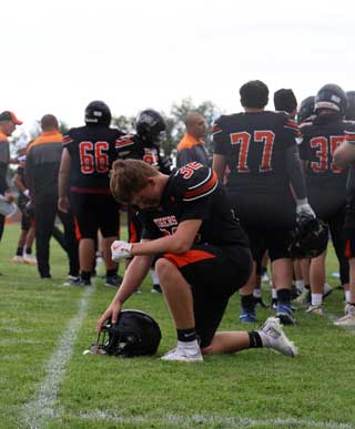 Student looking down while kneeling behind the team