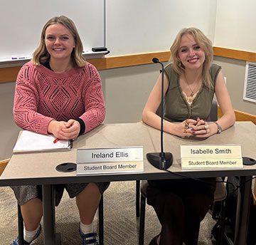 Two student board members sitting at a table