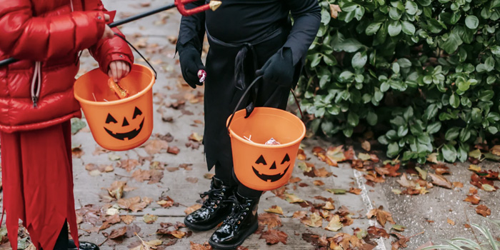 Two elementary students dressed for Halloween and holding pumpkin baskets